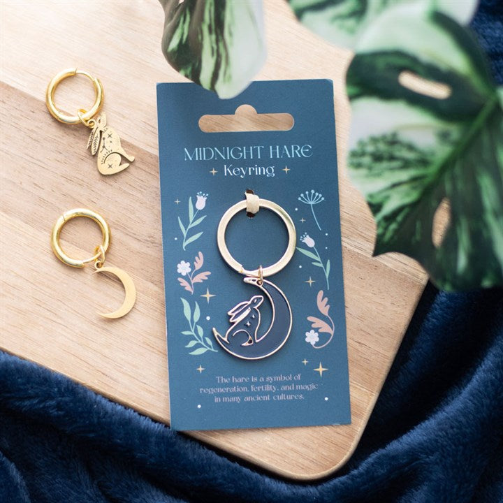 Midnight Hare keyring lifestyle shot on wooden board with navy fabric and monstera leaf