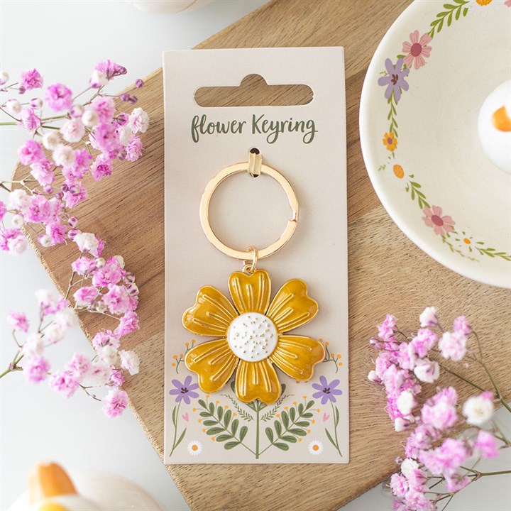 Yellow daisy flower keyring lifestyle shot on wooden board with pink gypsophila flowers and floral mug